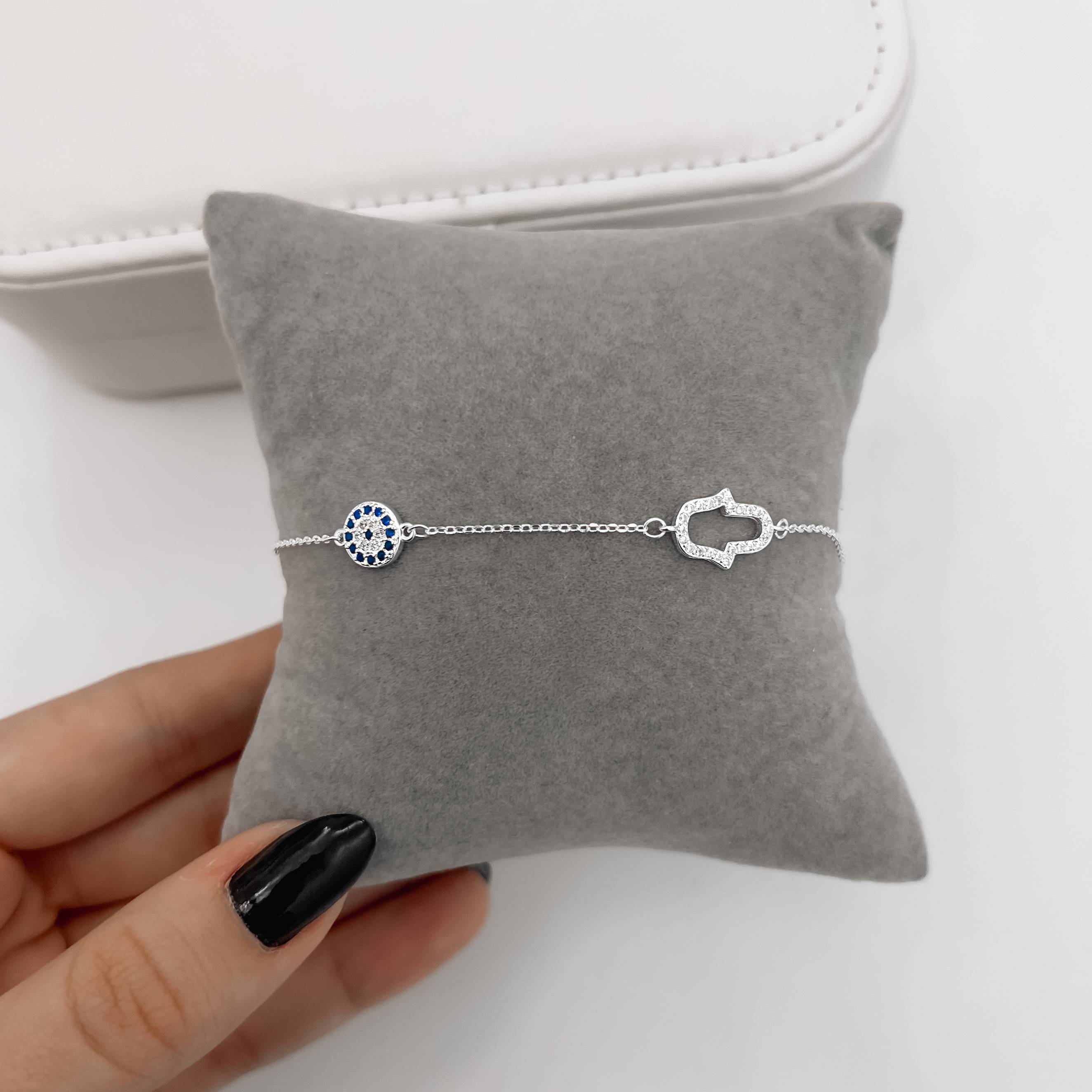 Pulseira entremeios mão vazada e olho grego cravejados 